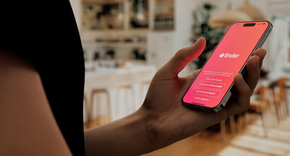 Mann hält ein Smartphone in der Hand mit der Tinder App auf dem Display - er braucht gute Pick-Up-Lines